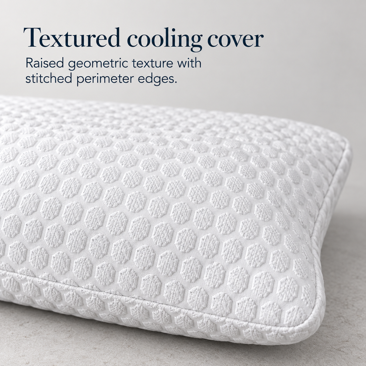Close view of a white pillow cover showing its raised repeating geometric texture, softly rounded corner and stitched perimeter edge.