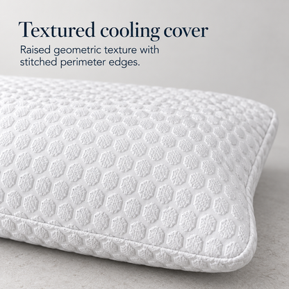 Close view of a white pillow cover showing its raised repeating geometric texture, softly rounded corner and stitched perimeter edge.