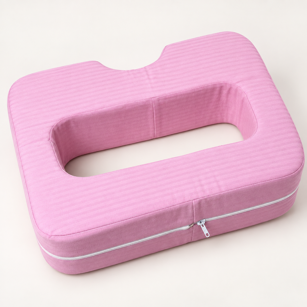 Pink cotton-covered chest support pillow with open centre and curved neck notch