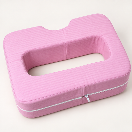 Pink cotton-covered chest support pillow with open centre and curved neck notch